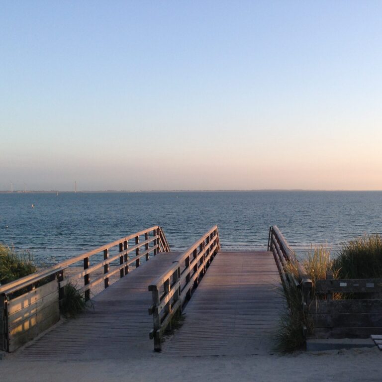 Vlonder leidt naar de zee bij zonsondergang