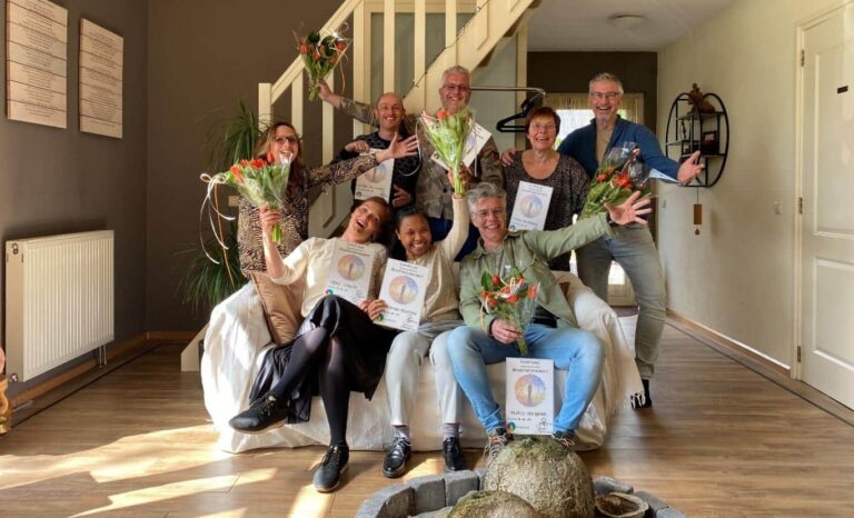 Cursisten poseren na het afronden van de 15 delen met hun certificaat en bloemen.