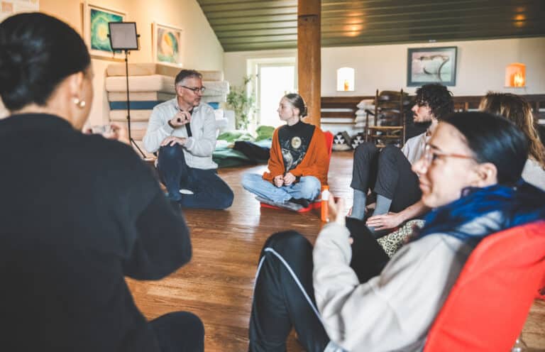 Marco zit in een kring tijdens een retreat 1.0, in gesprek met deelnemers.