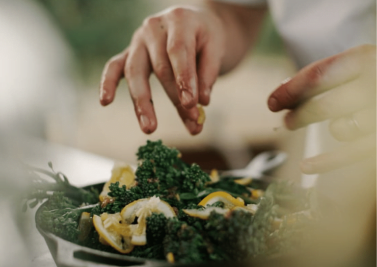 Handen bereiden maaltijd met broccoli en citroen