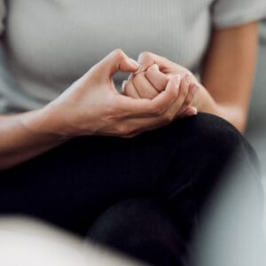 vrouw zit alleen en plukt aan de huid bij haar nagels, teken van angst