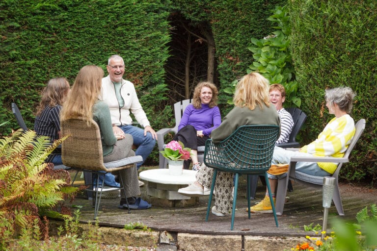 Groep lacht en praat samen buiten bij het Breathfulness Center.