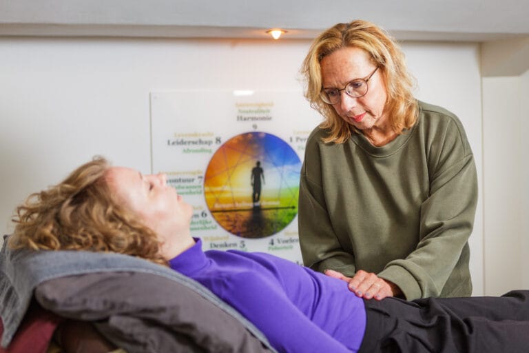Jacquelien legt haar hand op de buik van een klant tijdens een ademsessie.
